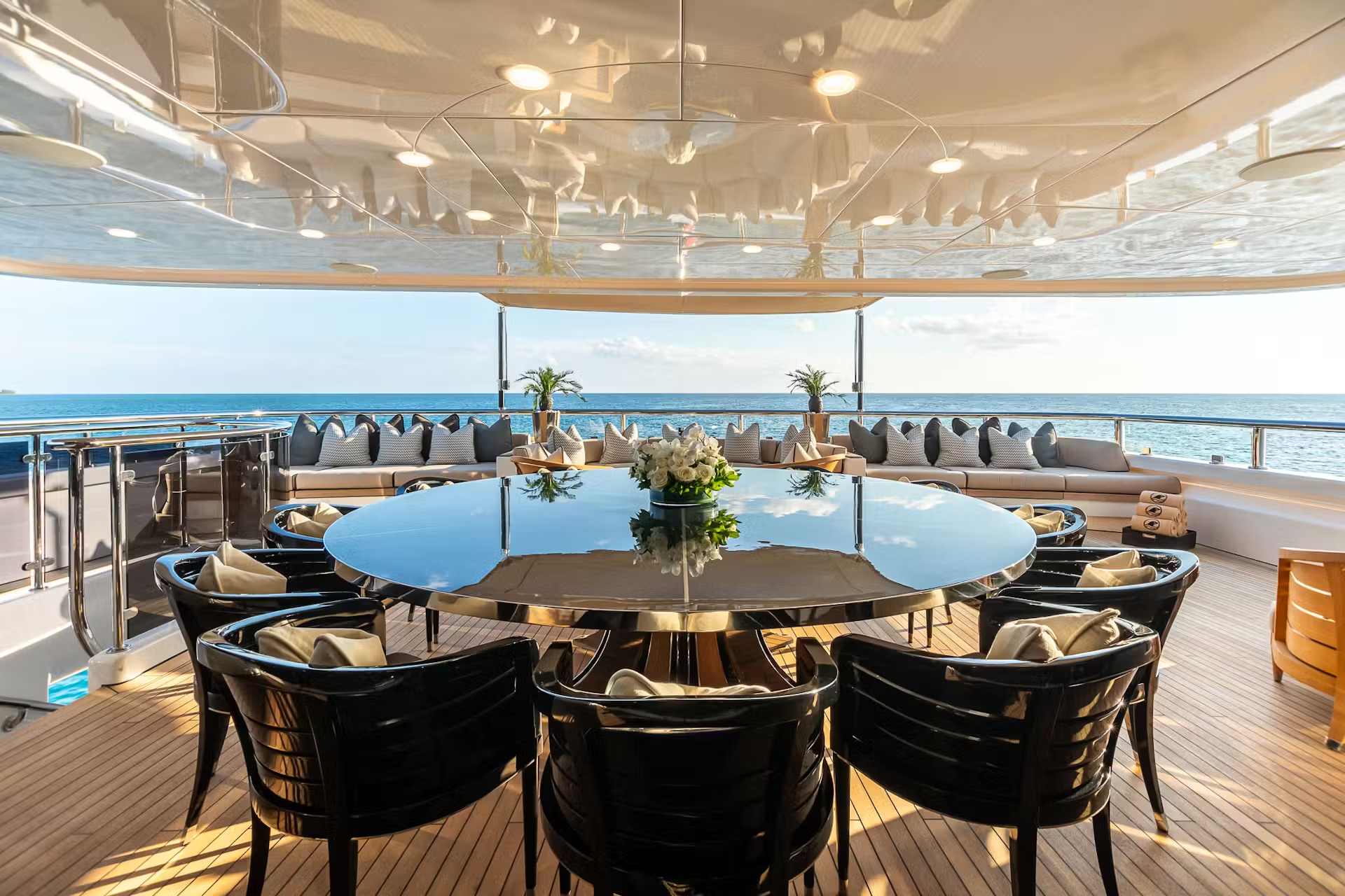 Main salon with dining table, white floral centerpiece, ocean views, and crew member attending to guests.