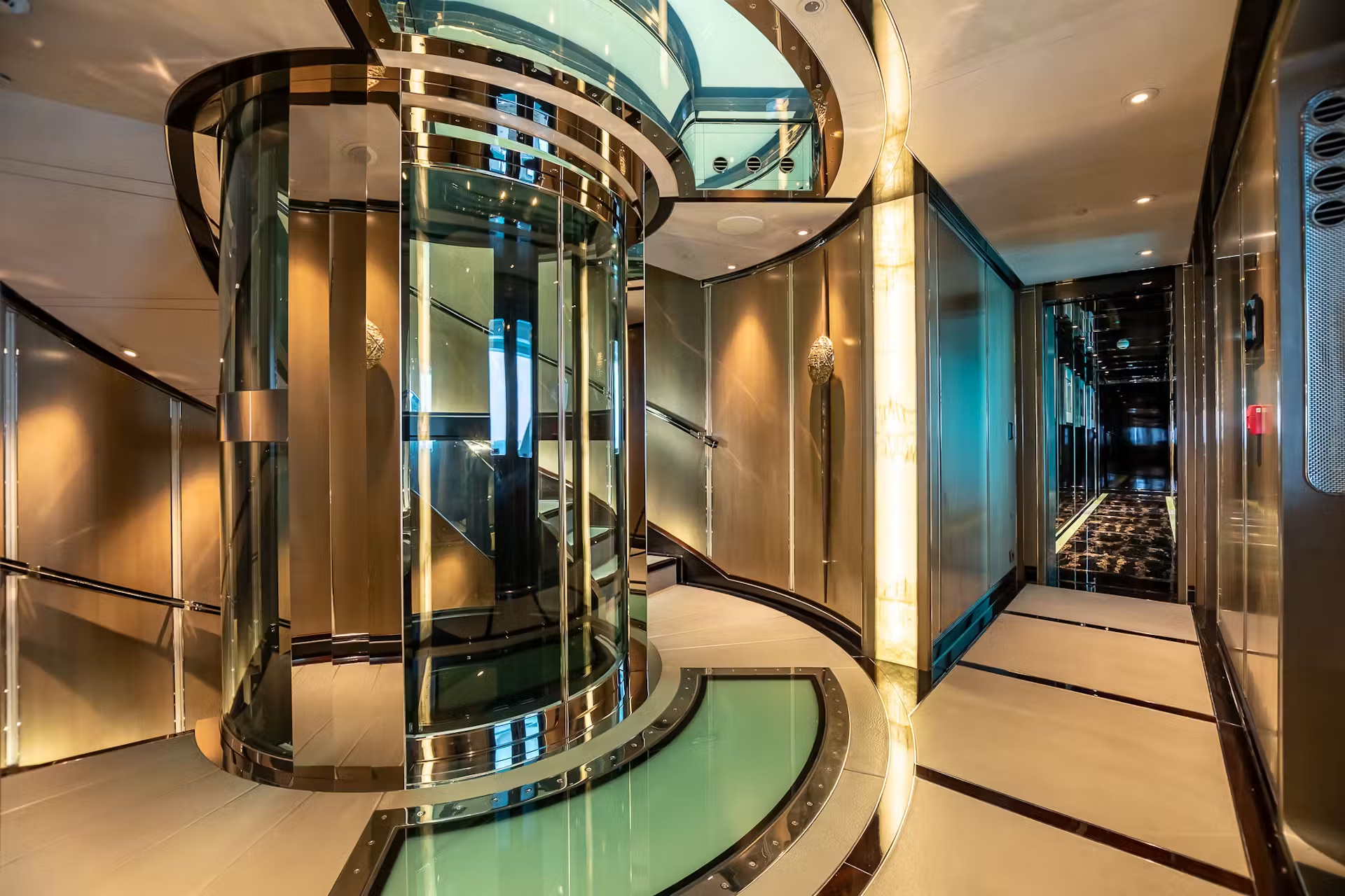 Contemporary curved glass elevator with teal panels, metallic trim and minimalist yacht interior.