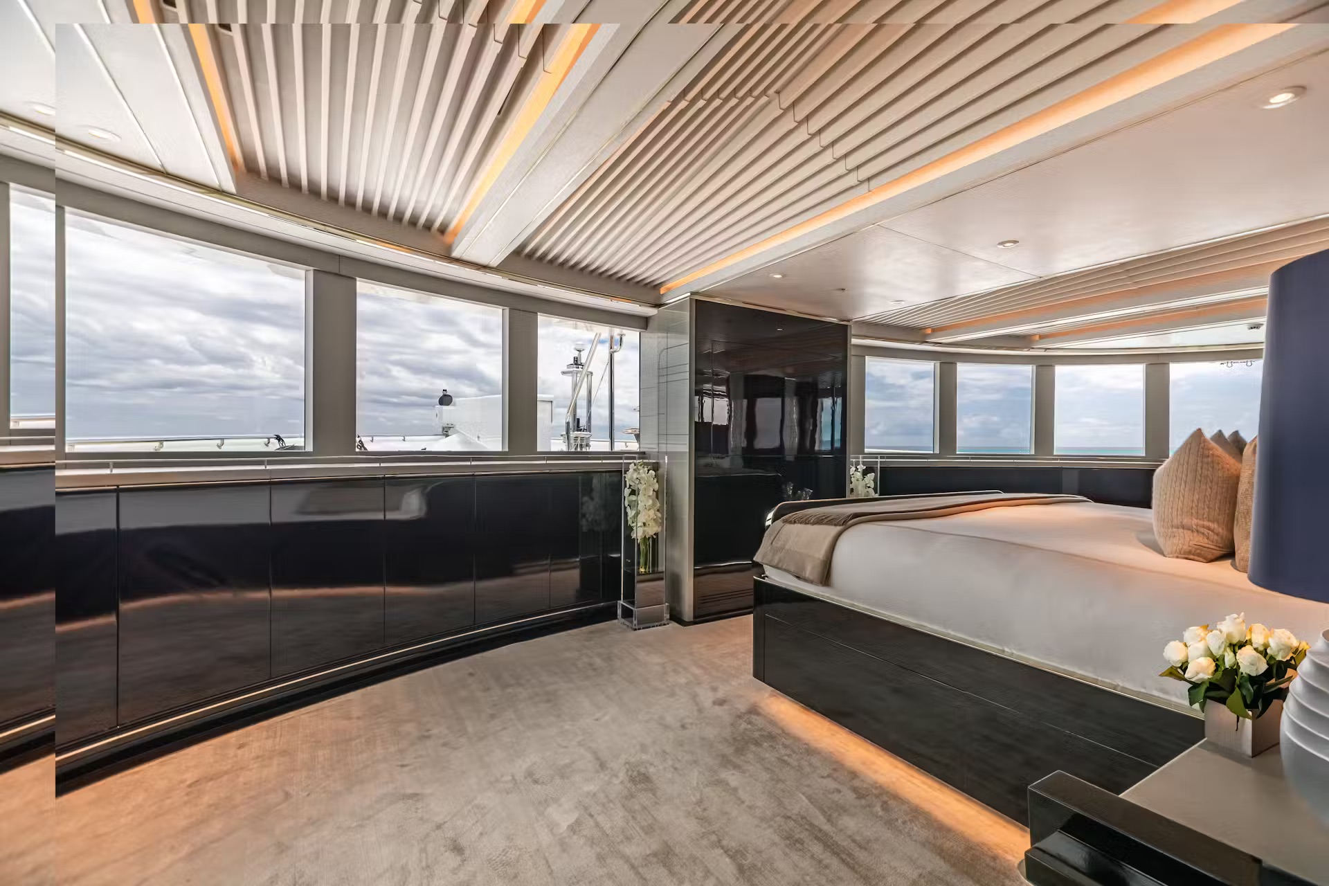 Elegant main deck lounge with grand piano, cream seating, sculptural table and sophisticated night lighting.