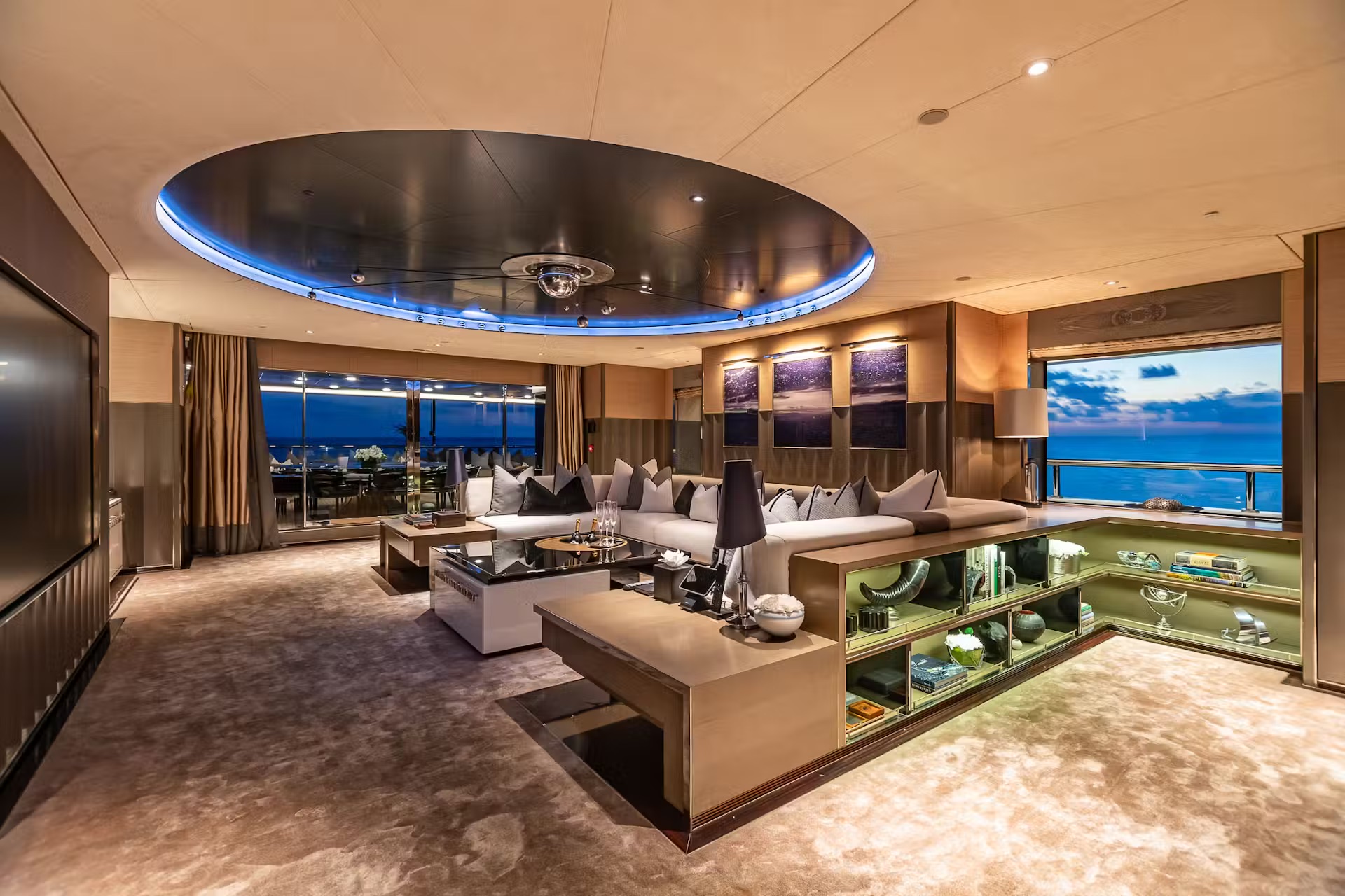 Owner's deck lounge with blue-illuminated oval ceiling, contemporary furnishings and panoramic coastal views.