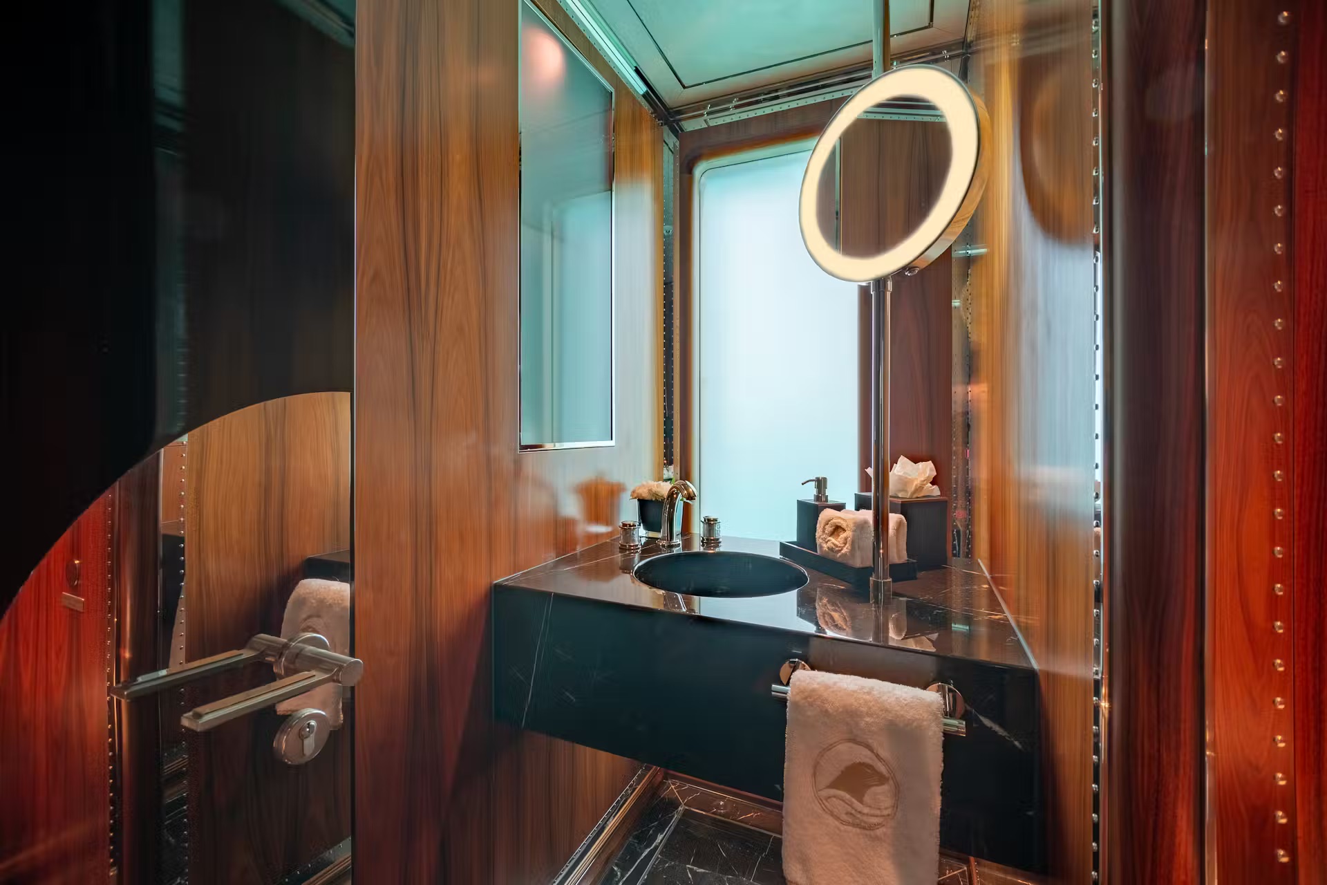 Luxury yacht bathroom with marble walls, dark sink basin, and brass fixtures