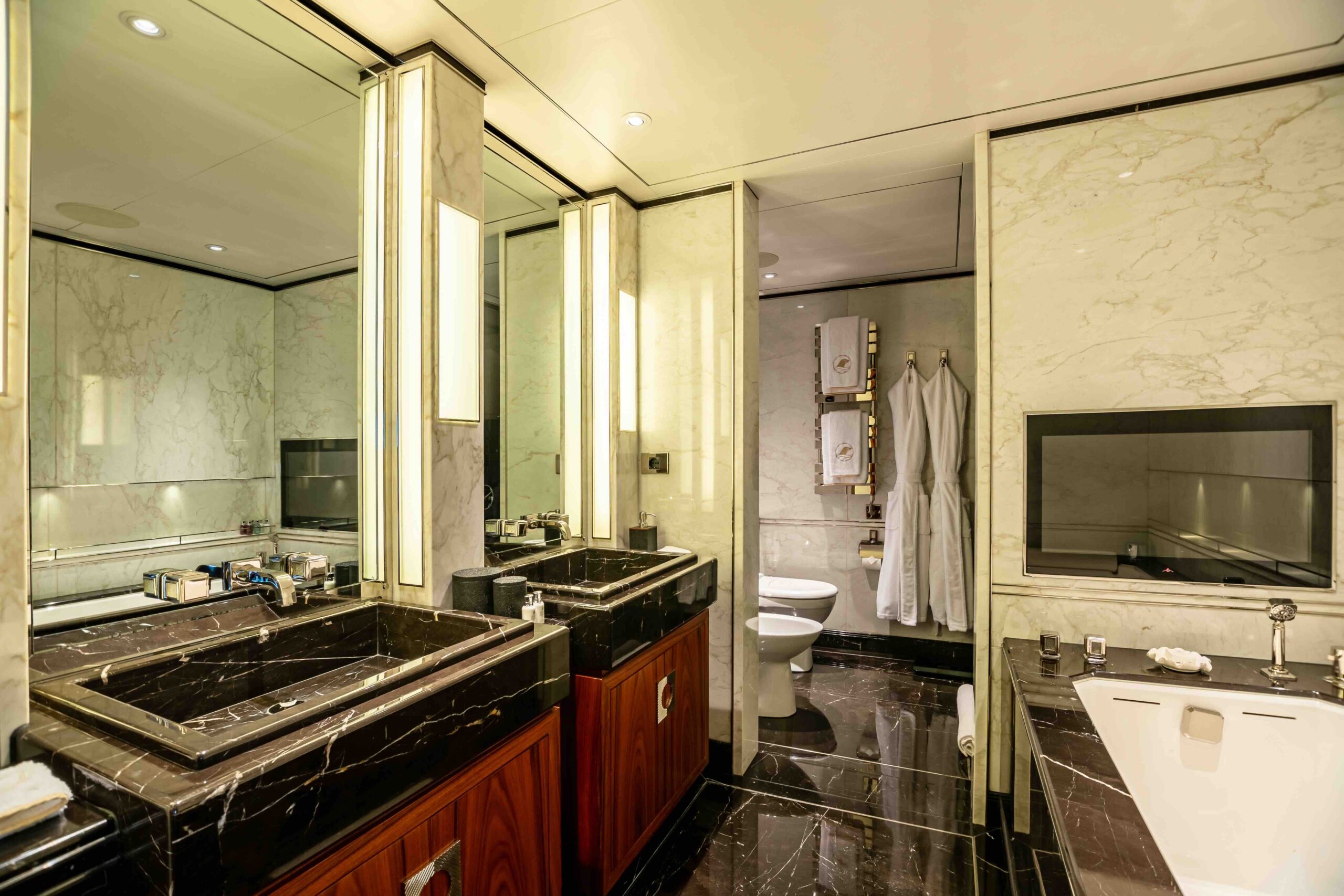 Salerno cabin ensuite with marble walls, dual vanity, gold-trimmed mirrors, and ambient lighting